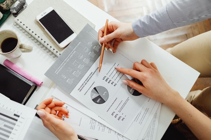 Two people reviewing printed payroll reports at a desk
